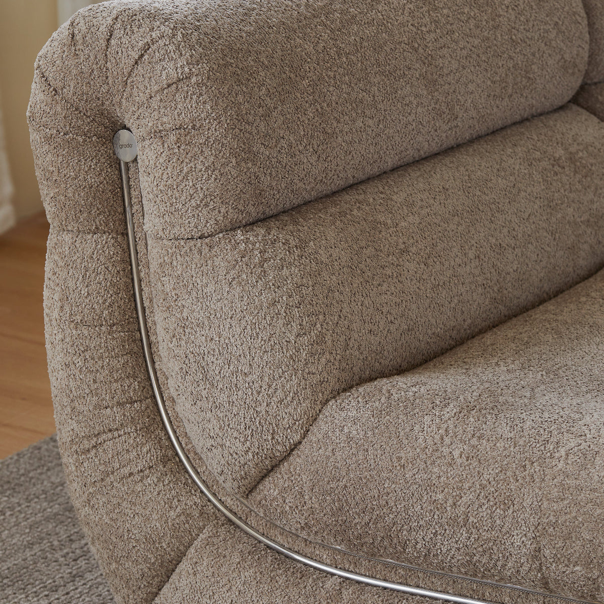 Close-up of a beige upholstered chair with a metallic armrest.