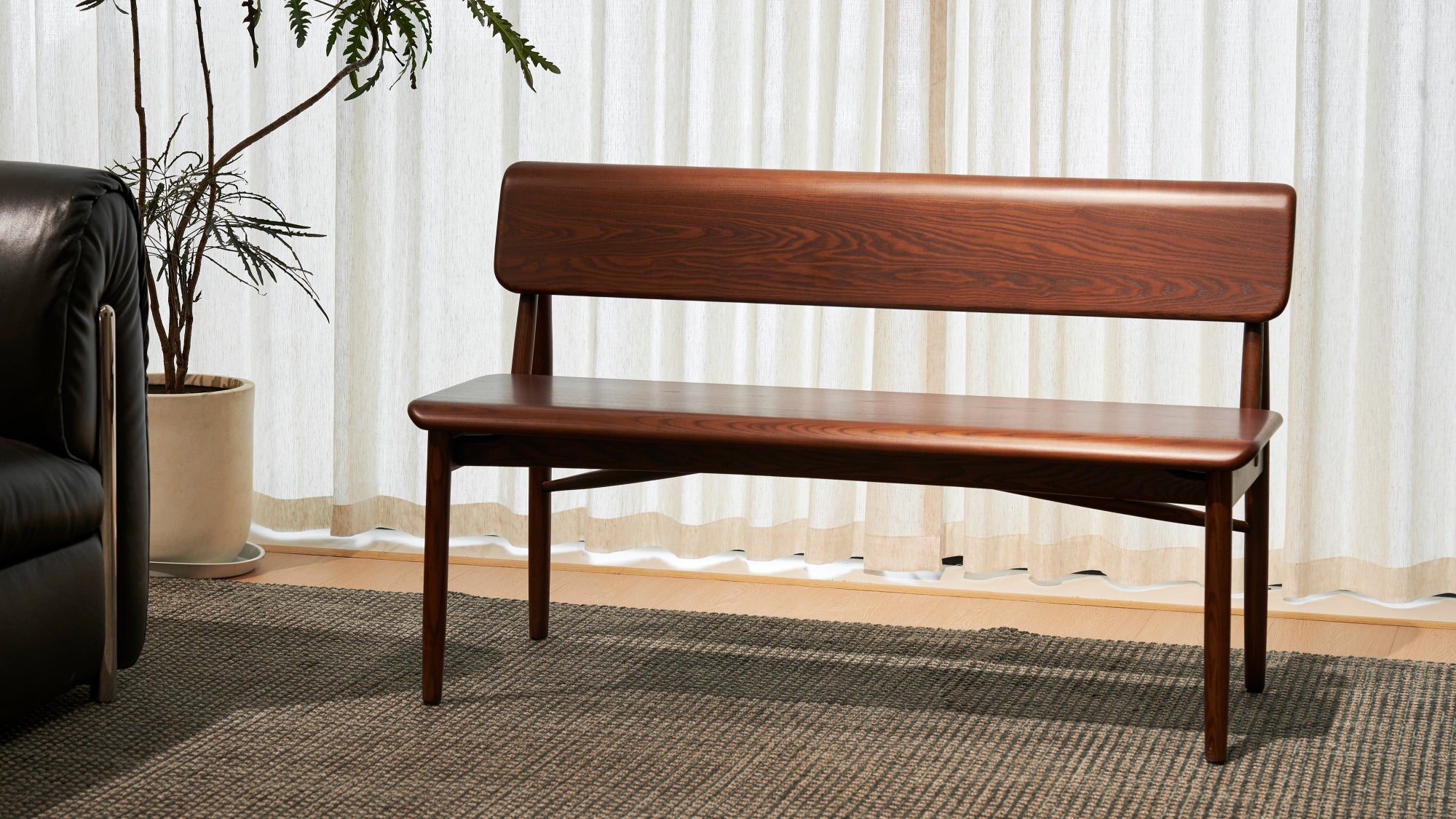 Wooden bench in a living room setting with a plant and sofa.