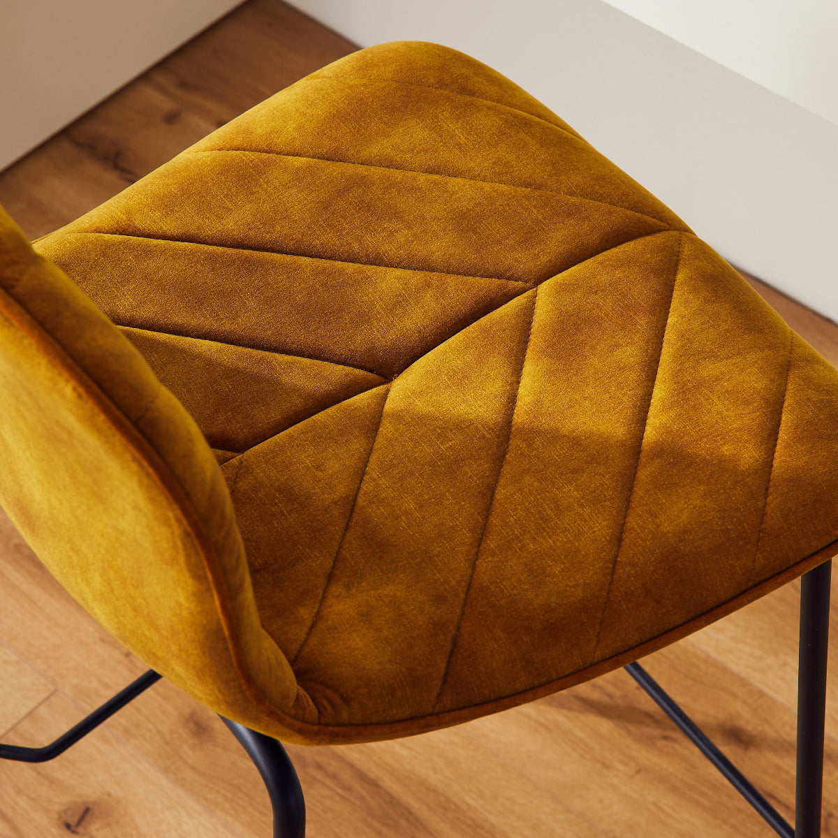 Mustard yellow chair with quilted design on a wooden floor