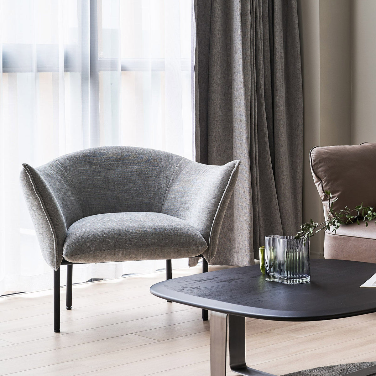 Modern living room with a gray armchair, coffee table, and curtains.