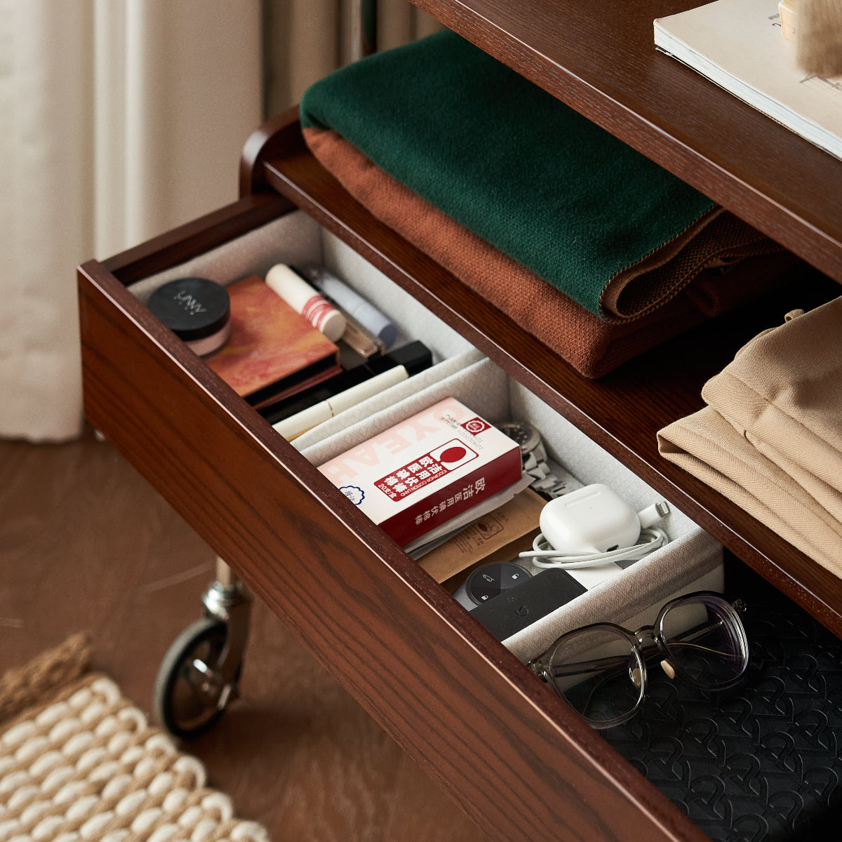 Wooden drawer with various items including a box of tissues and a pair of glasses.