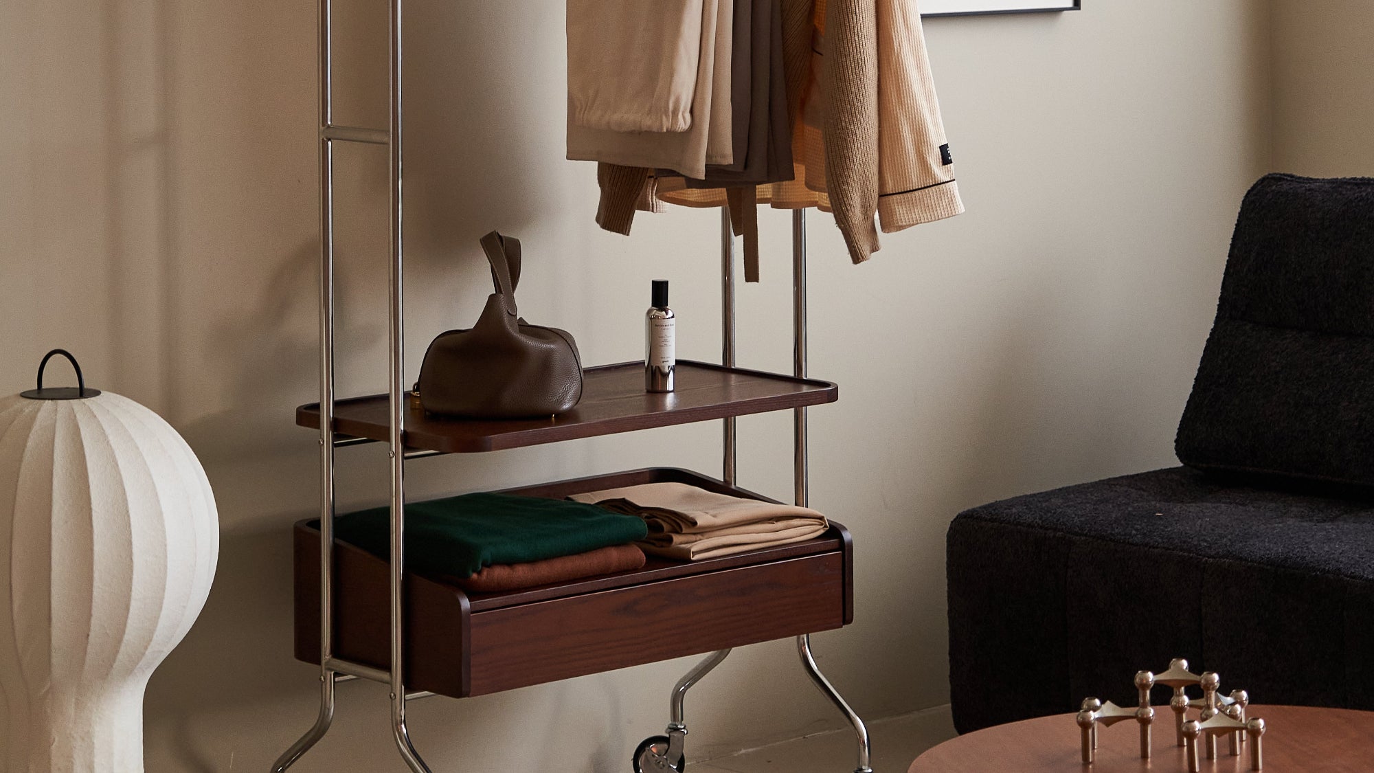 Clothing rack with clothes in a room with a sofa and table.