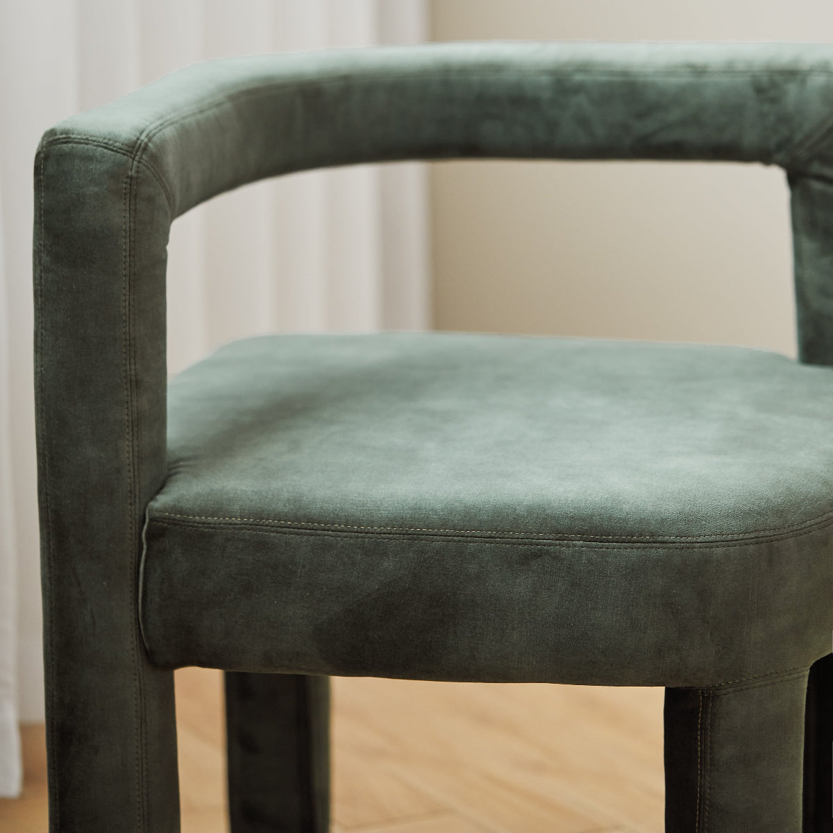 Green velvet chair against a neutral background