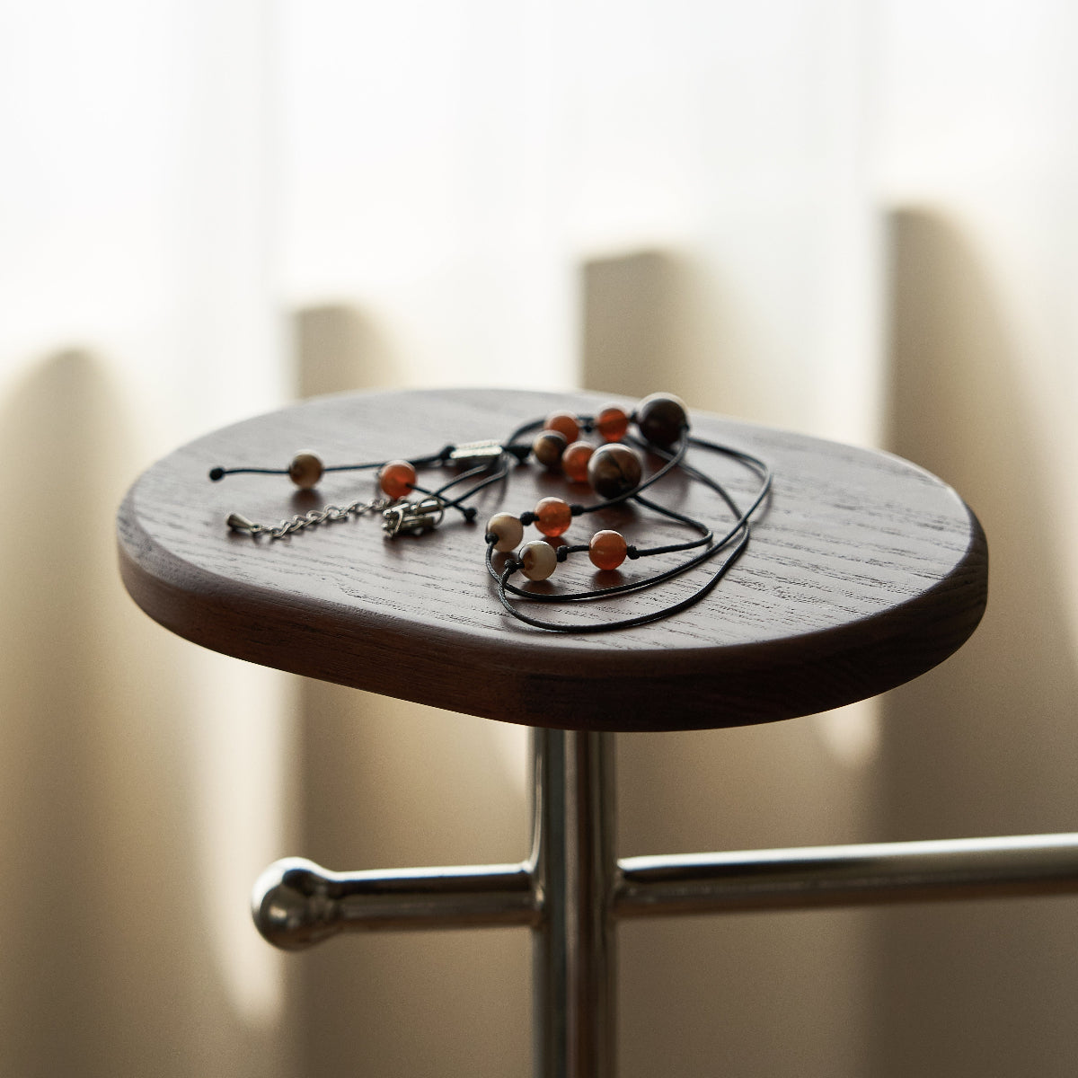 Small round wooden table with a necklace on a blurred background