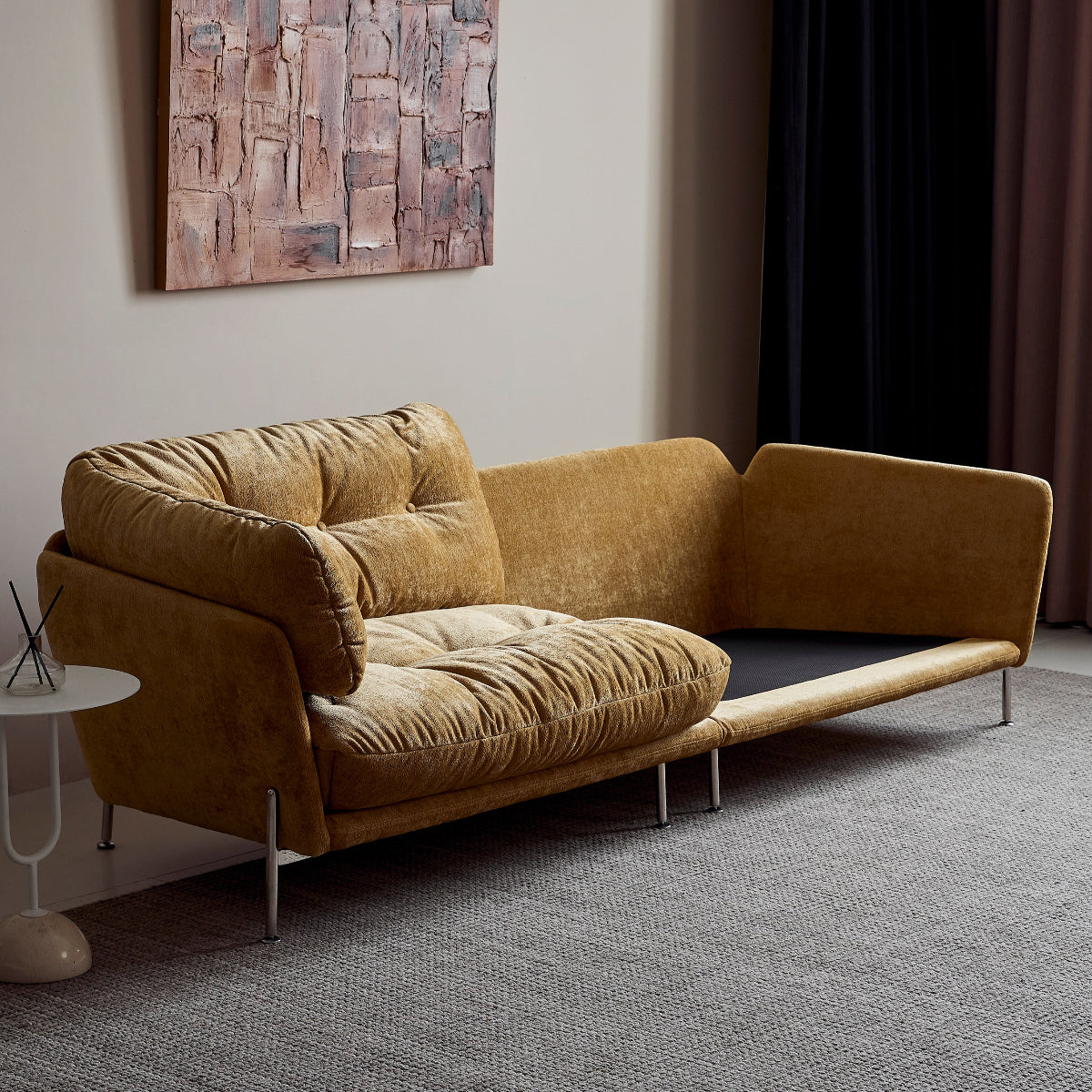 Modern yellow sofa in a room with abstract art on the wall and dark curtains.