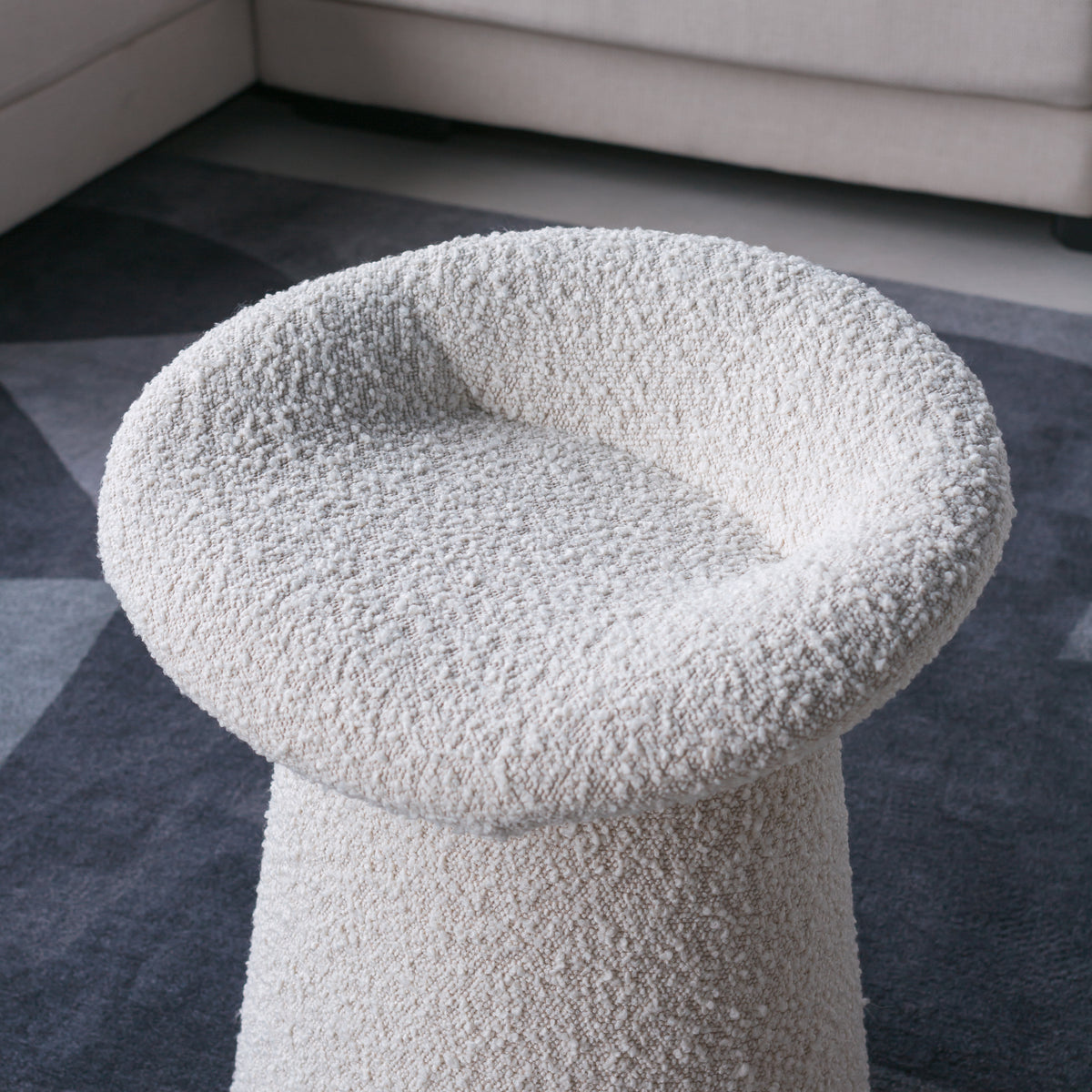 White textured stool on a gray carpeted floor