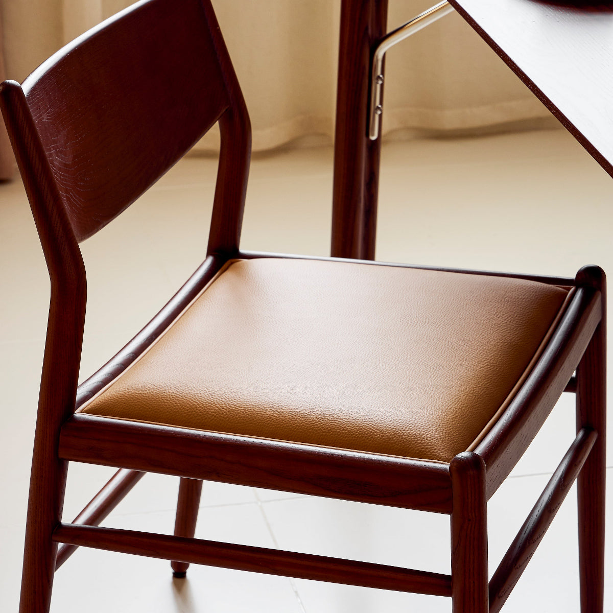 Wooden chair with a brown cushion on a light-colored floor.