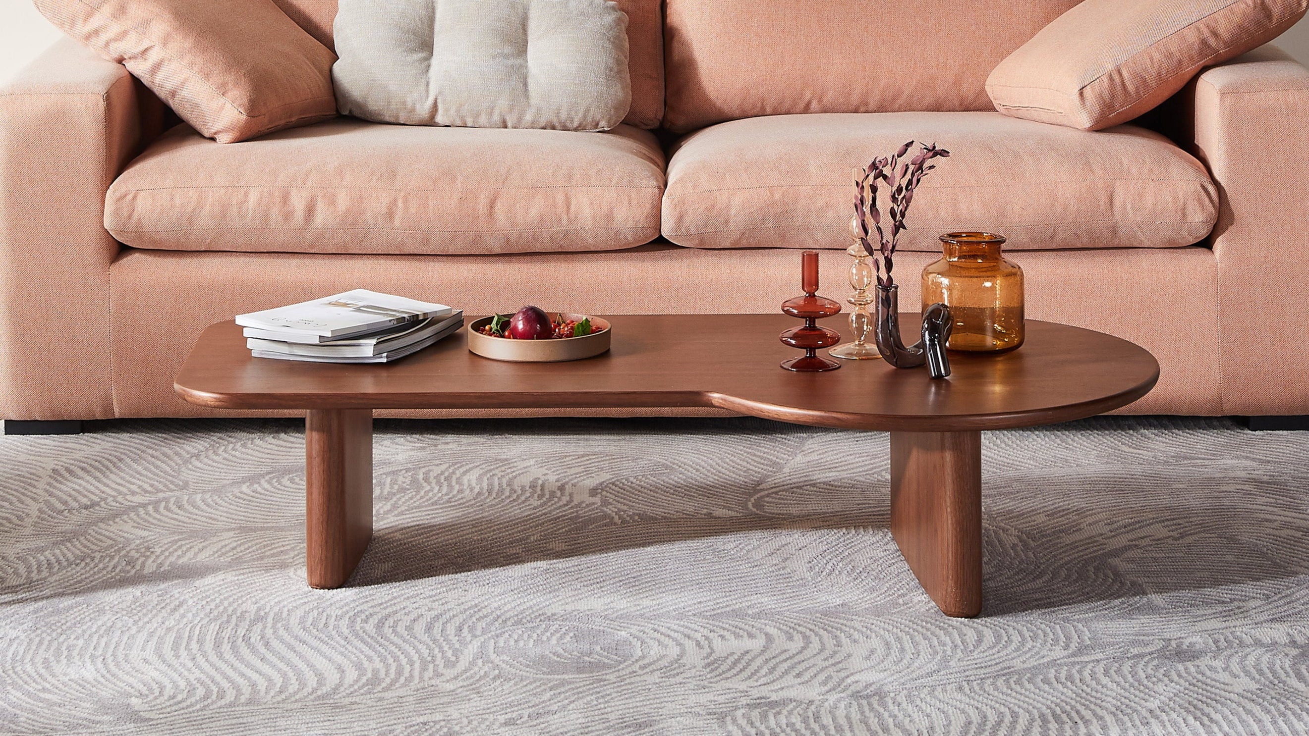 Modern living room with a pink sofa, wooden coffee table, and decorative items.