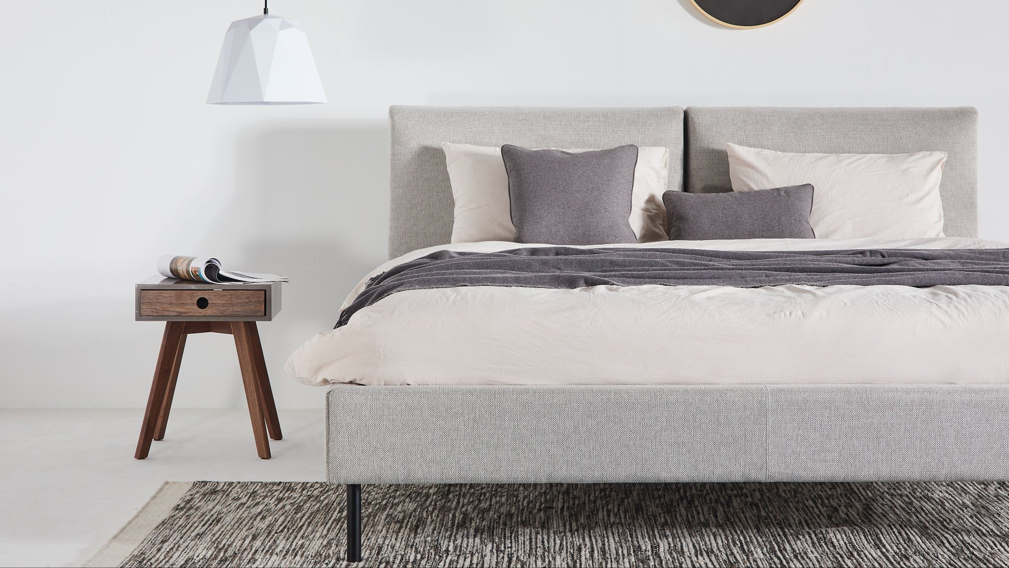 Modern bedroom with a gray bed, nightstand, and decorative wall light.