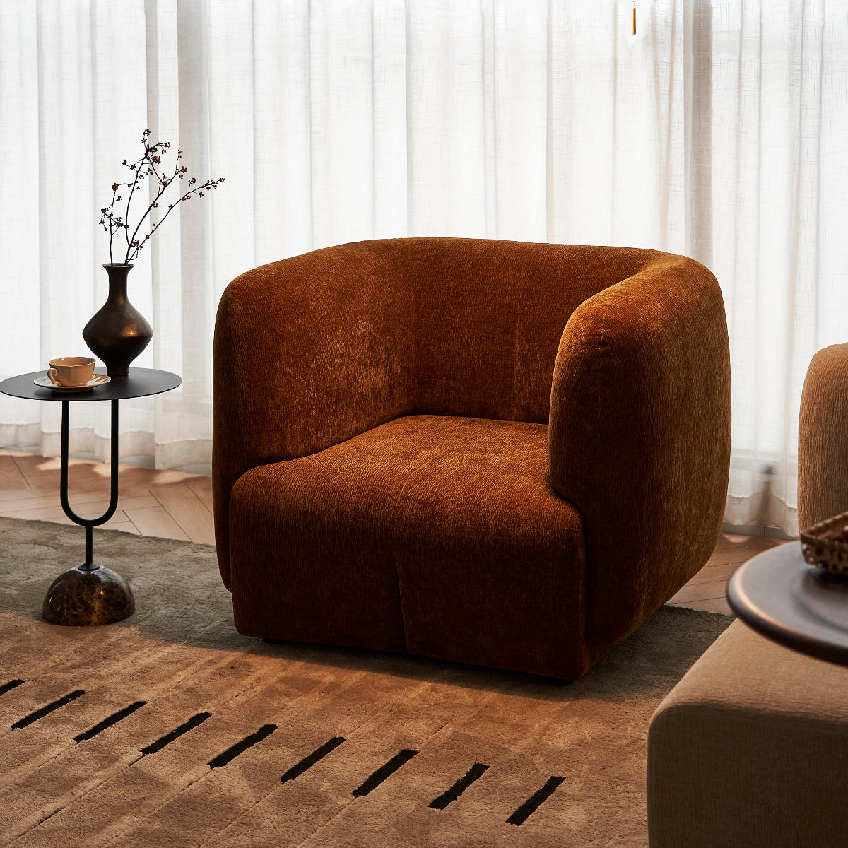 Brown armchair in a modern living room with a side table and lamp.