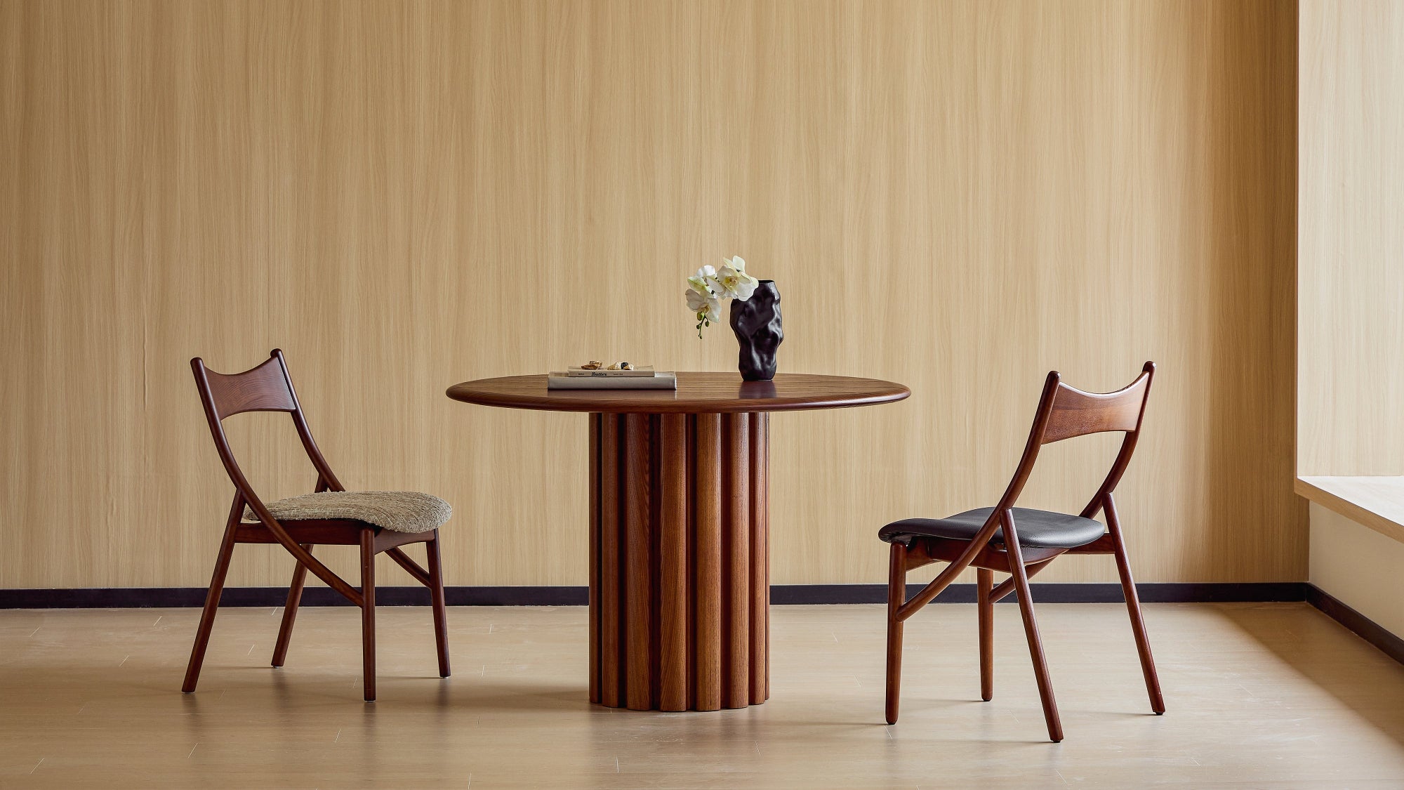 Wooden table with two chairs against a beige wall.