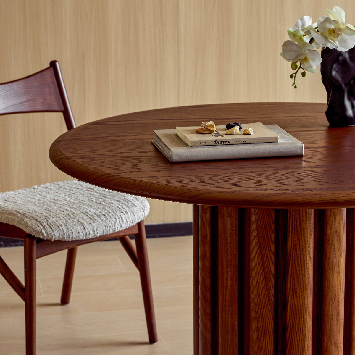 Wooden dining table with a chair and decorative items against a beige wall.