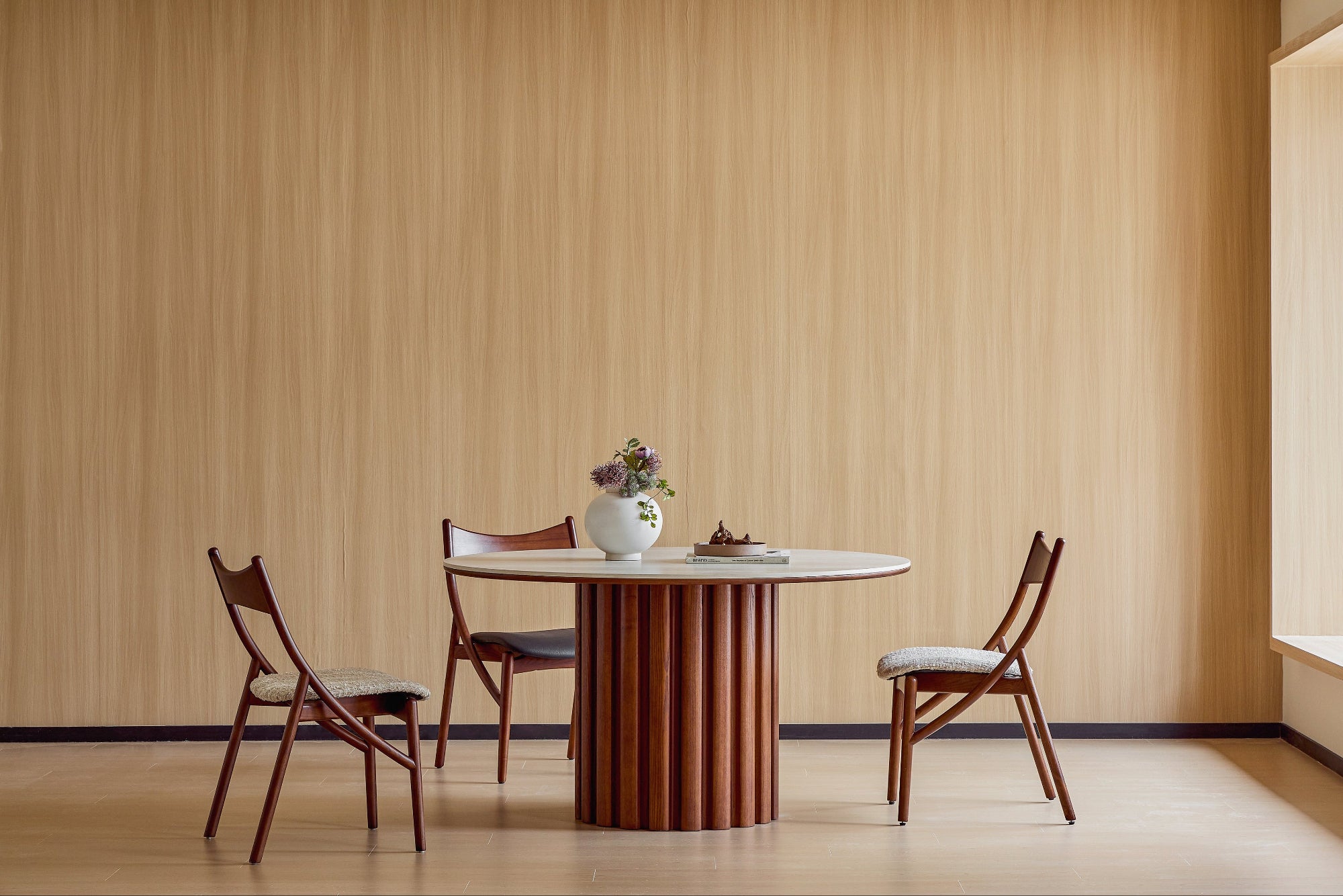 Dining table with chairs against a wooden paneled wall.