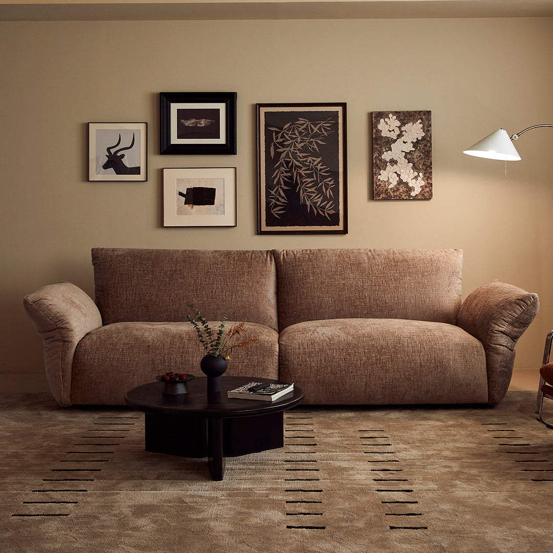 Living room with a brown sofa, coffee table, and wall art.
