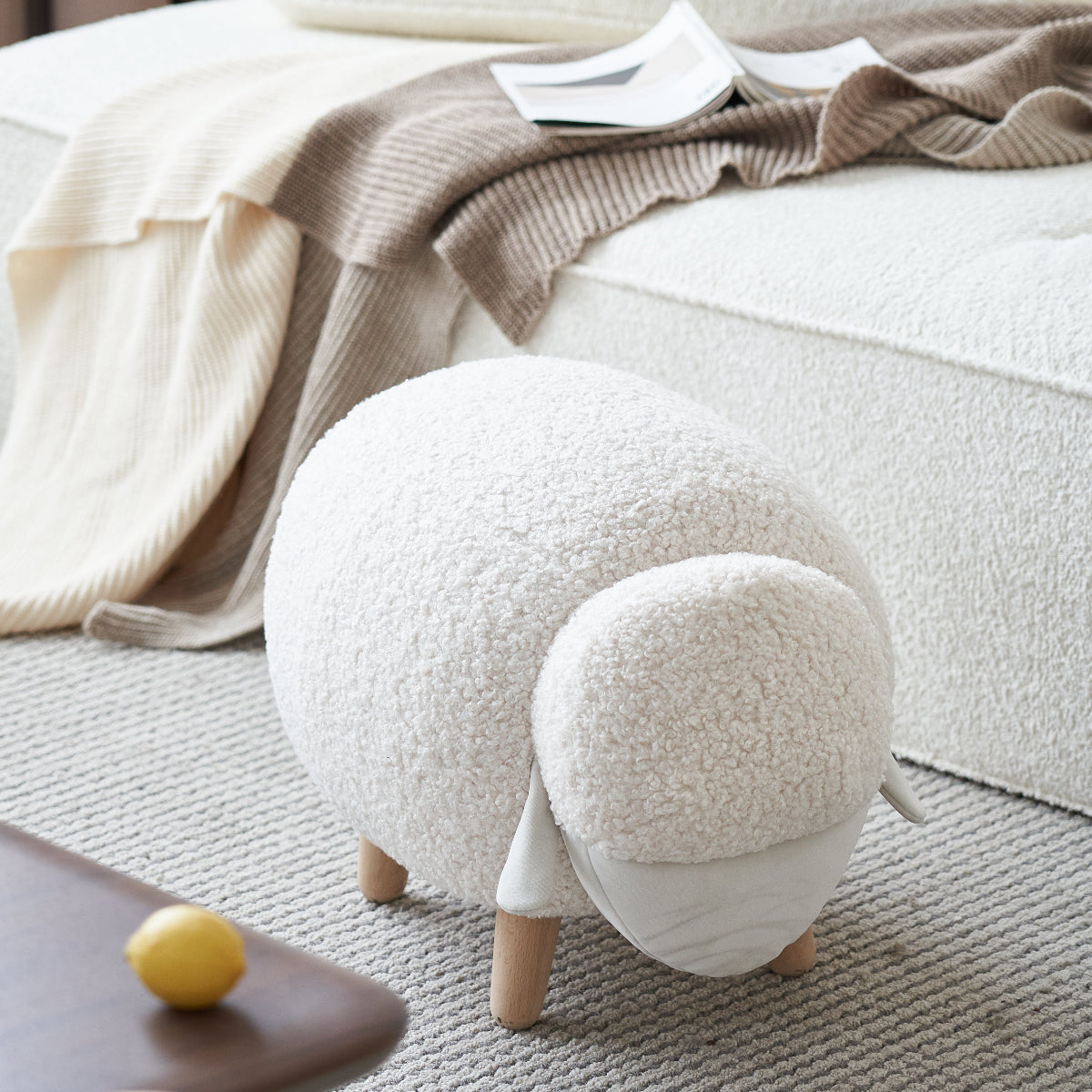 White textured ottoman in front of a white sofa with a blanket