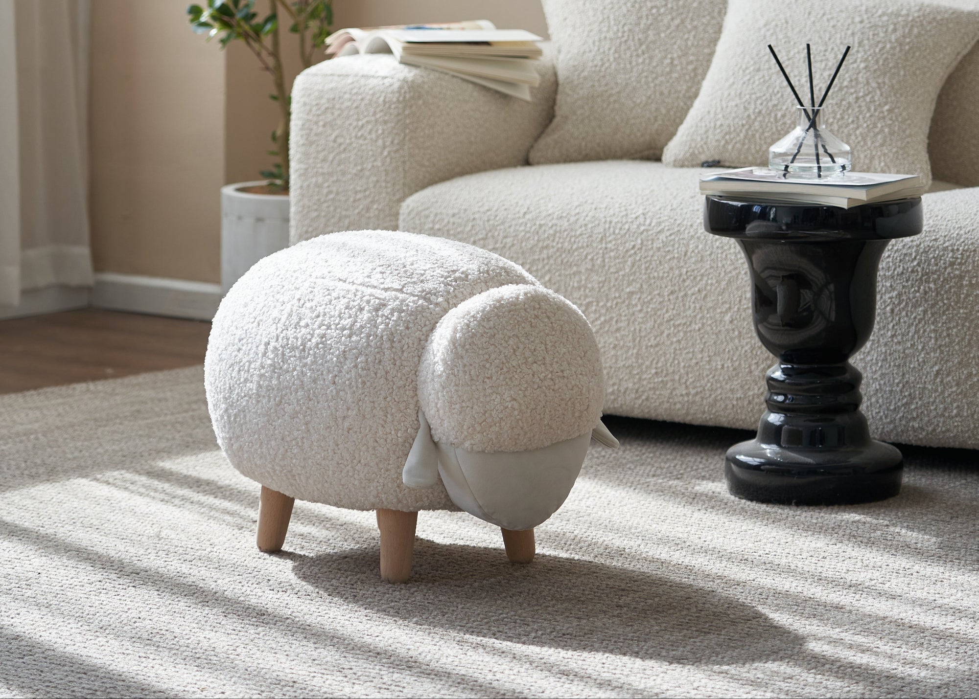 Modern living room with a white sofa, footstool, and decorative plant.