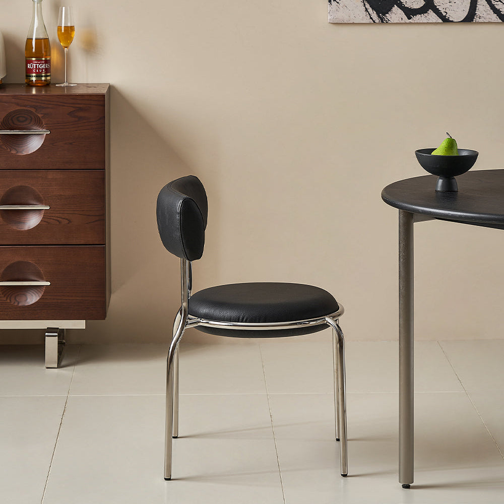 Modern black chair in a room with a wooden cabinet and abstract art on the wall.