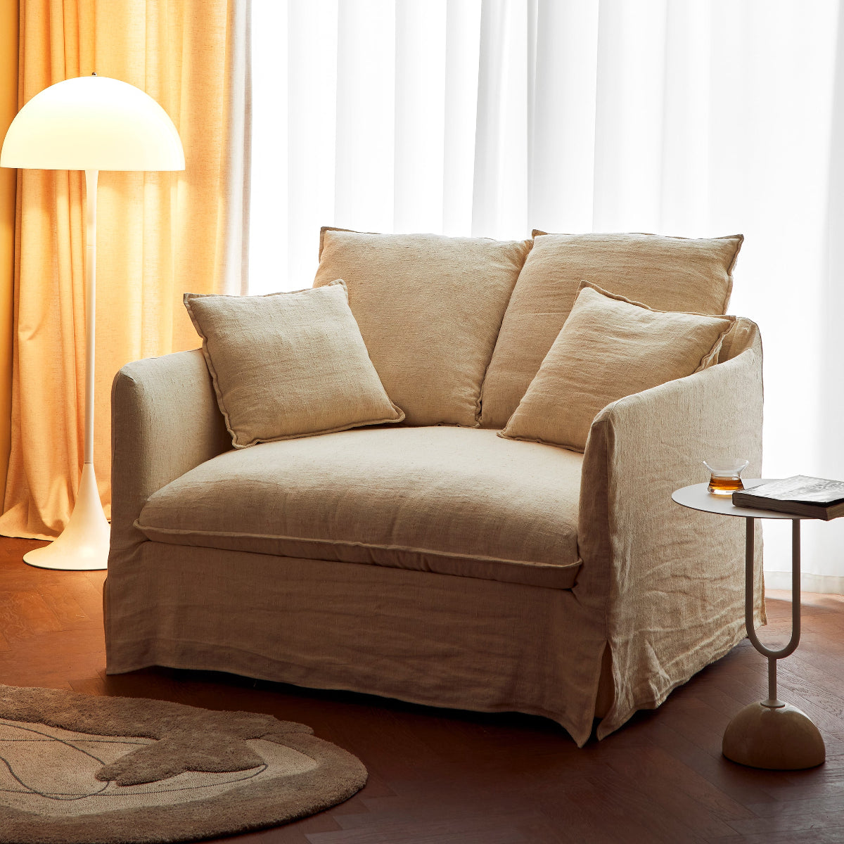 Beige armchair in a room with curtains and a side table.