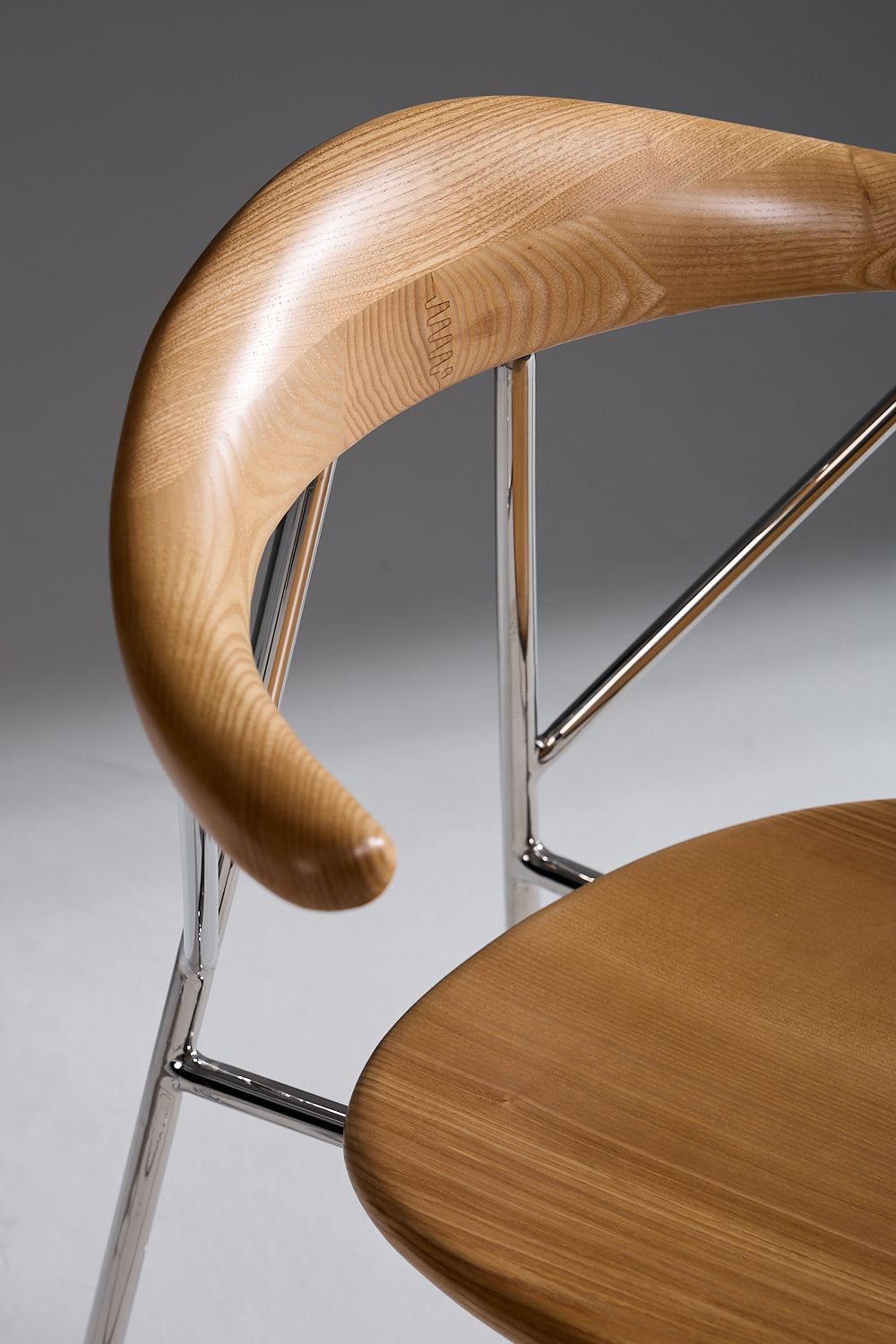 Wooden chair with curved armrest on a gray background