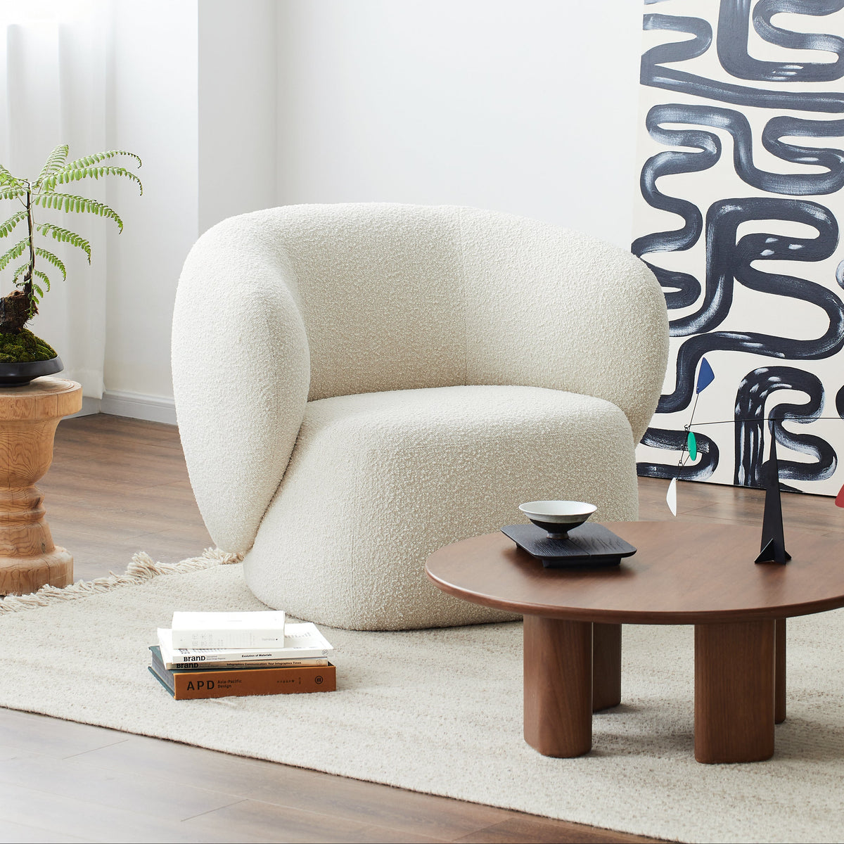 Modern living room with a white armchair, wooden coffee table, and abstract wall art.
