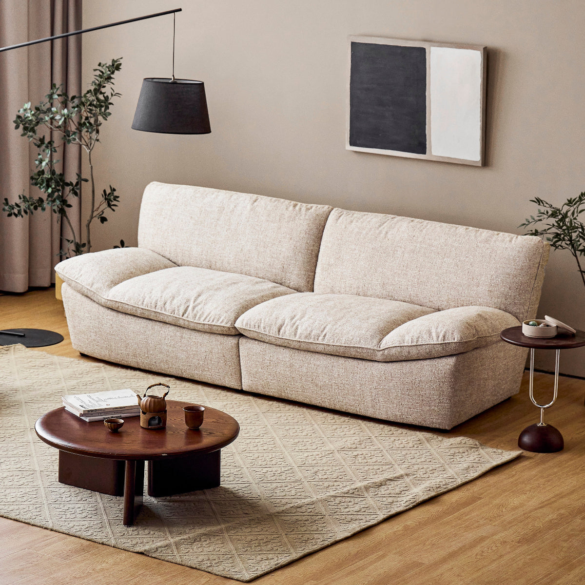 Modern living room with a beige sofa, round wooden coffee table, and decorative elements.