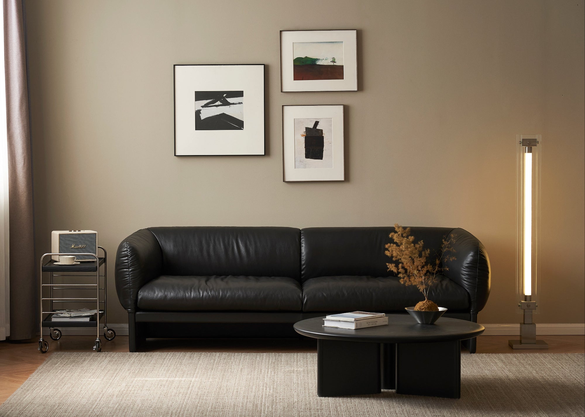 Modern living room with a black leather sofa, coffee table, and wall art.