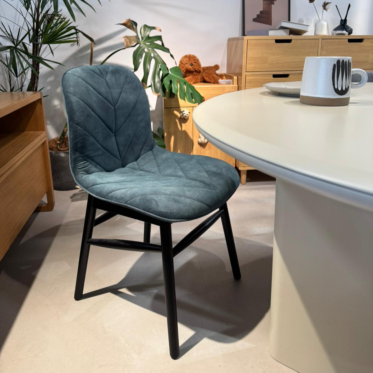Blue chair in a room with a table, plants, and furniture.