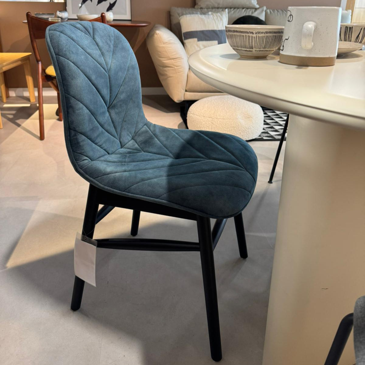 Blue cushioned chair in a room with a round mirror and dining table.