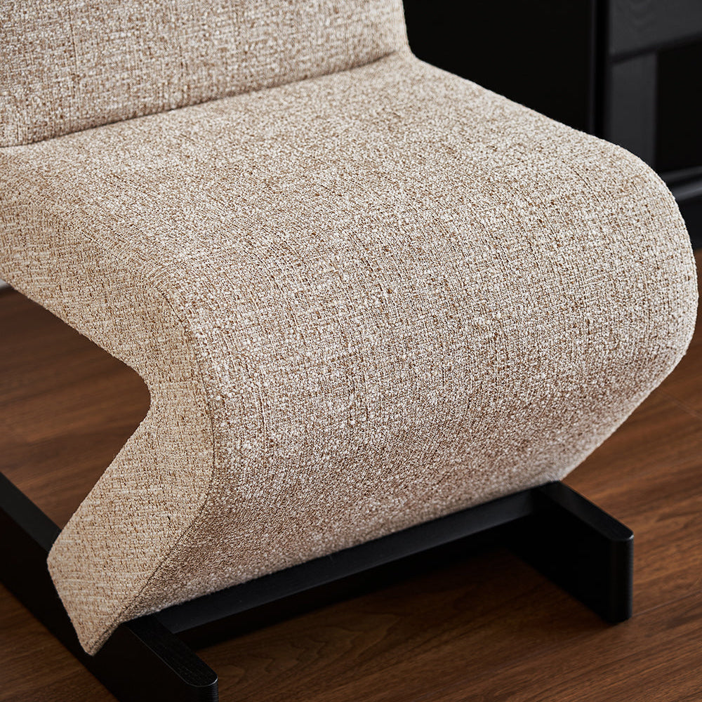 Beige upholstered chair with black metal frame on a wooden floor