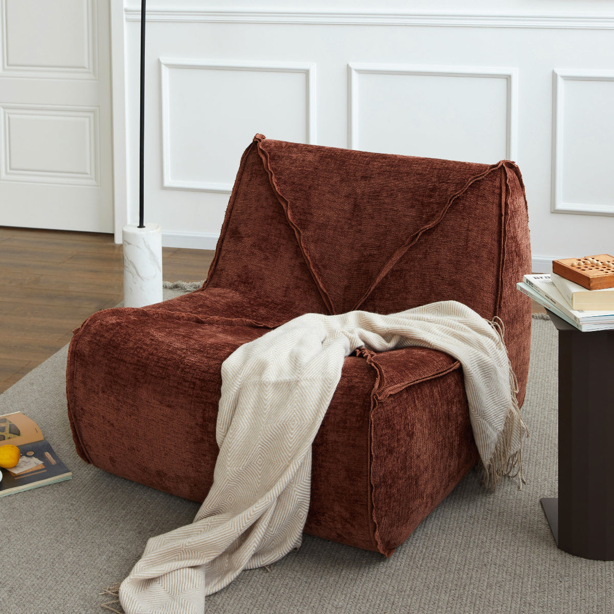 Brown懒人梳化 with a blanket draped over it in a room with a lamp and side table.