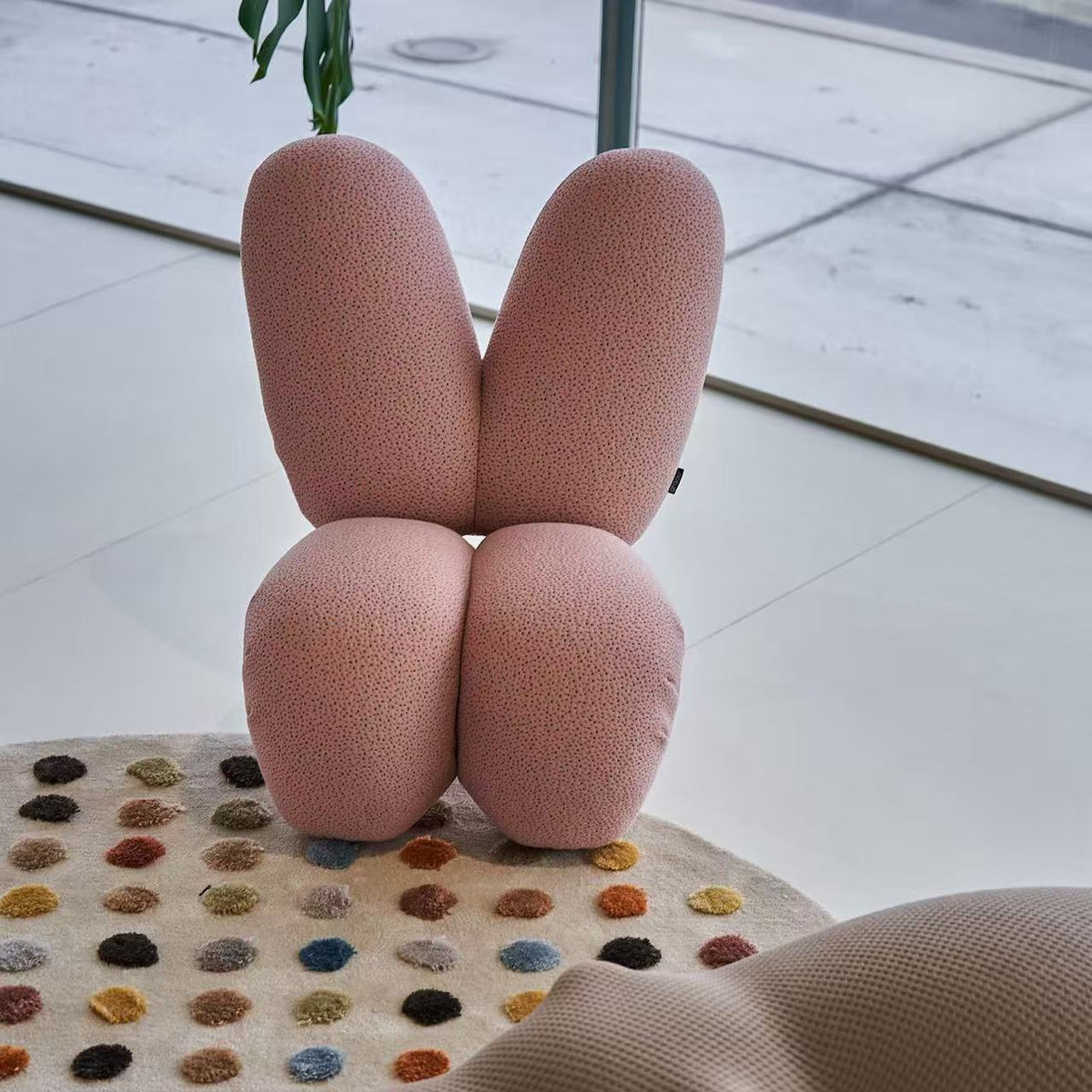 Pink abstract sculpture on a colorful rug with a tiled floor background