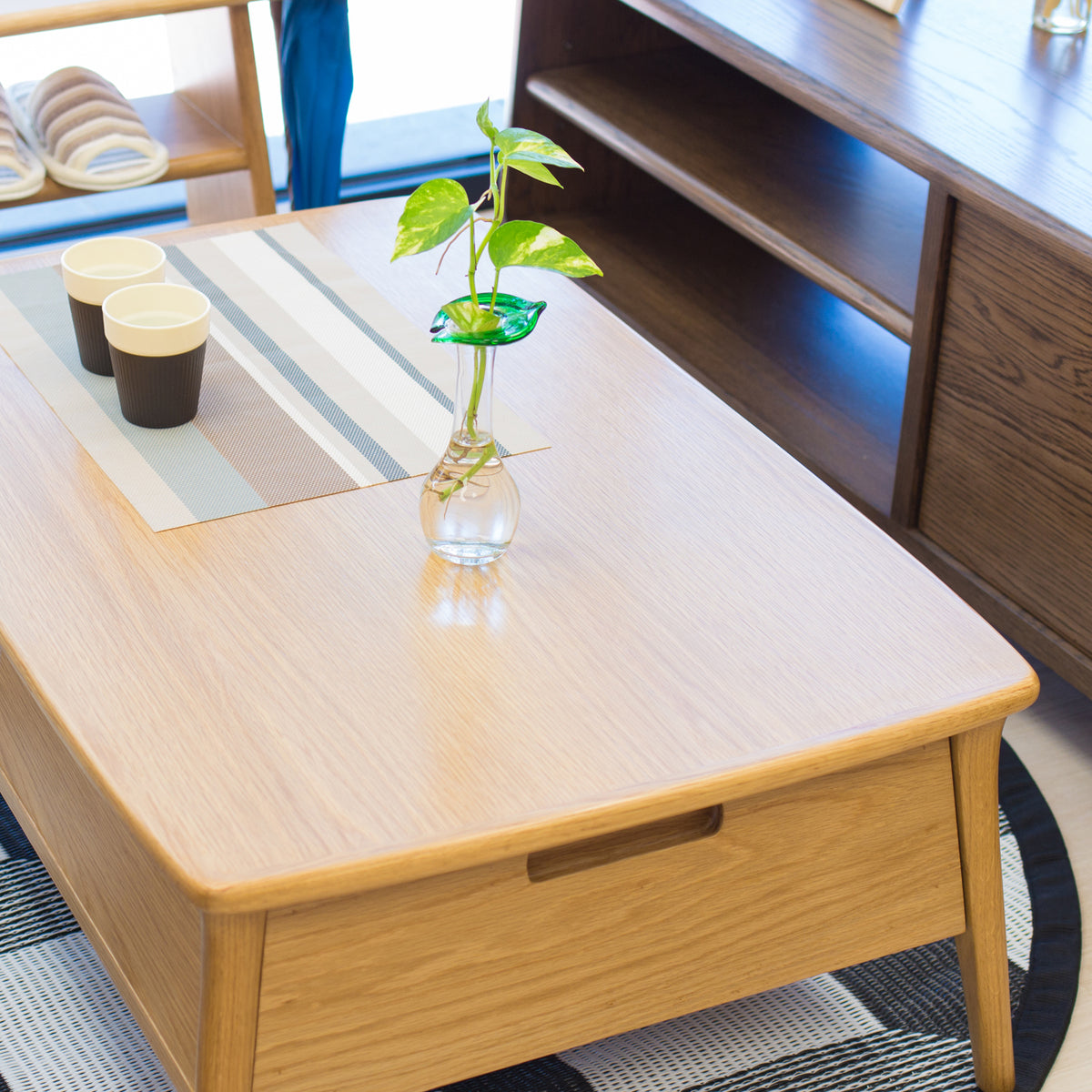 Wooden coffee table with a vase of green leaves in a room setting