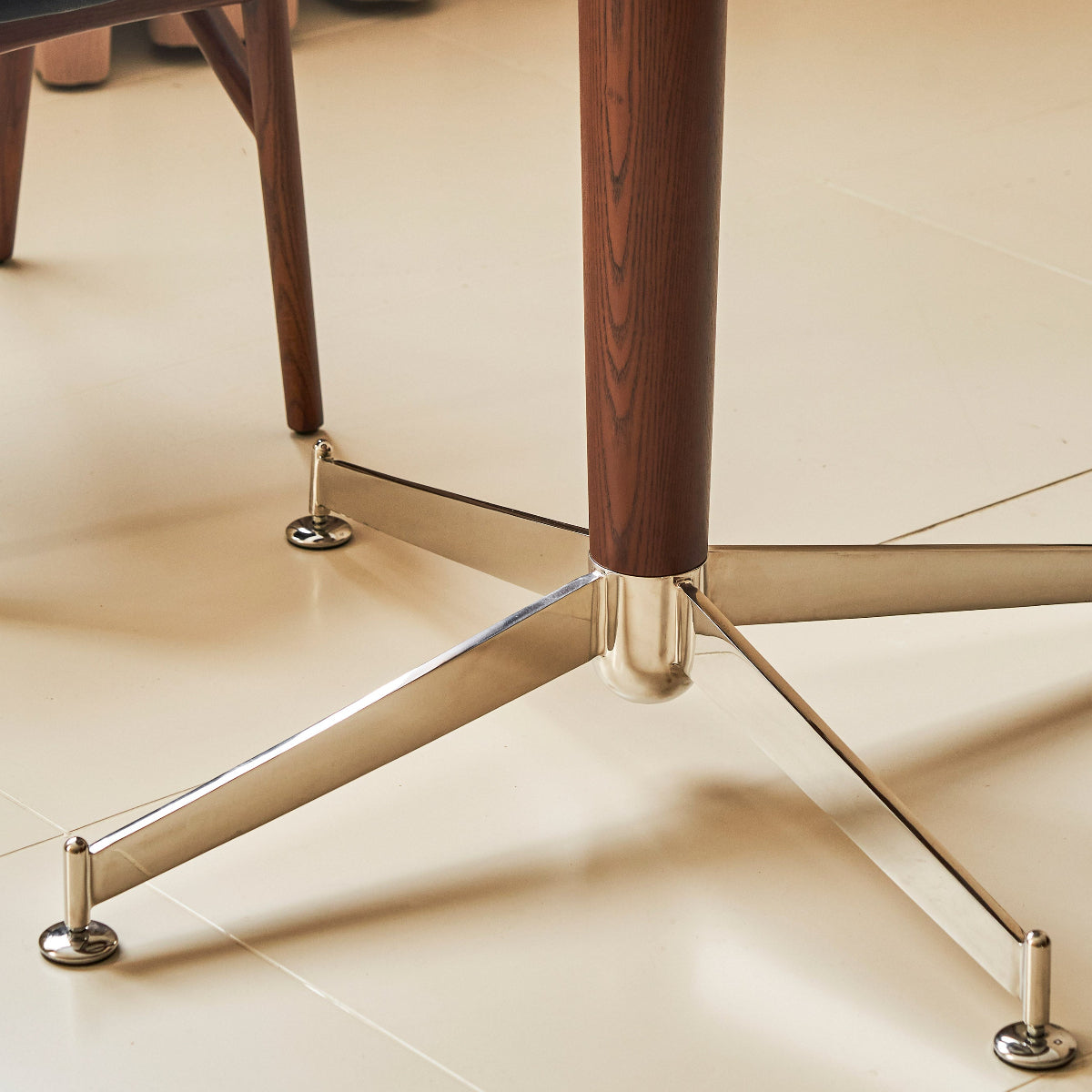 Close-up of a wooden table leg with metal base on a tiled floor