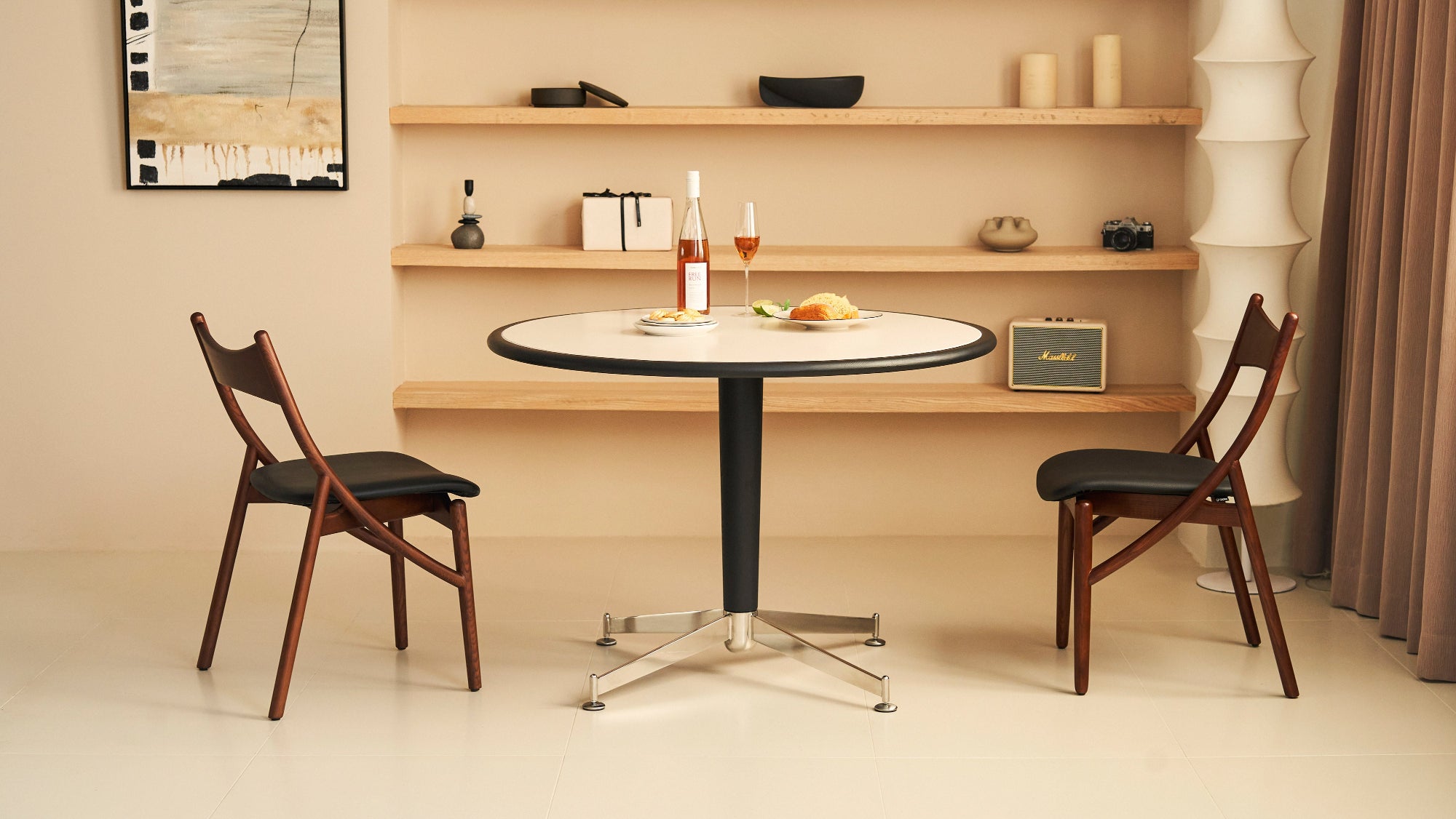 Small round table with two chairs in a room with wooden shelves.
